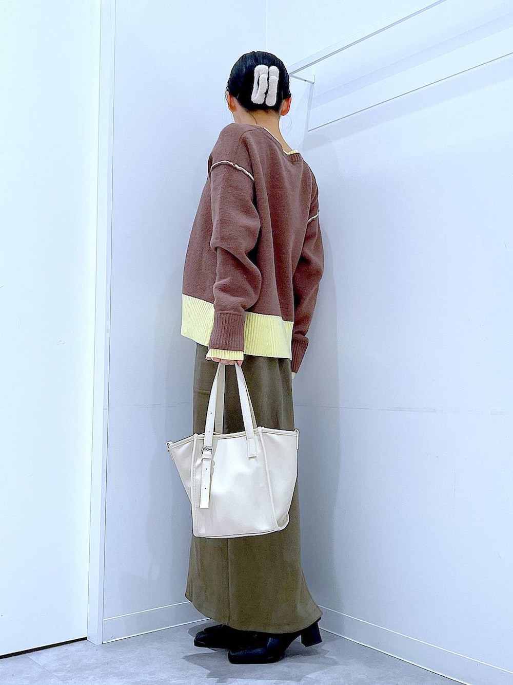 ブラック系のブーツ、グリーン系のスカート、ホワイト系のトートバッグを着用したレディースの冬コーディネートの3枚目の写真