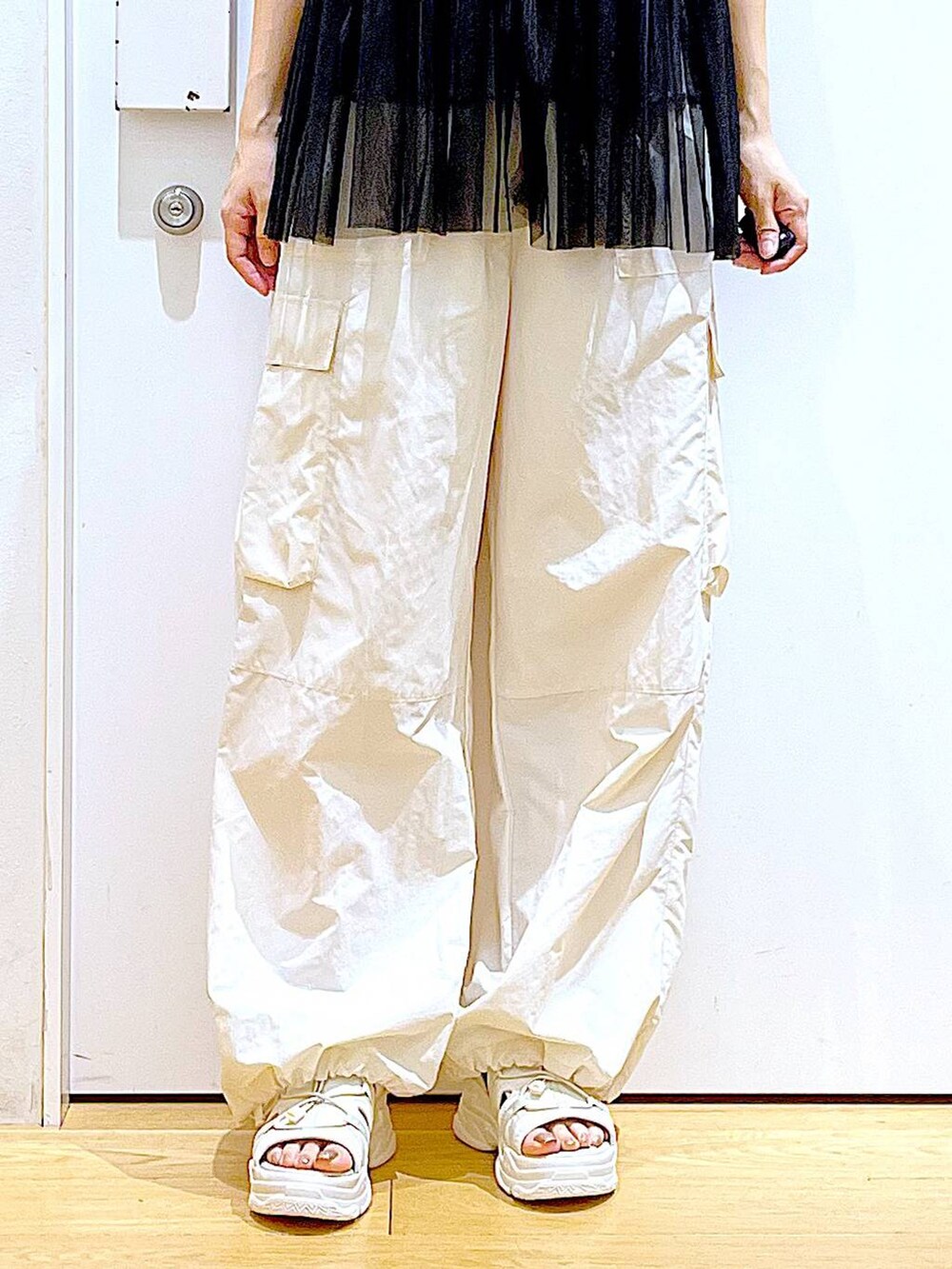 ブラック系のショルダーバッグ、ホワイト系のカーゴパンツ、ブラック系のキャミソールを着用したレディースの夏コーディネートの8枚目の写真