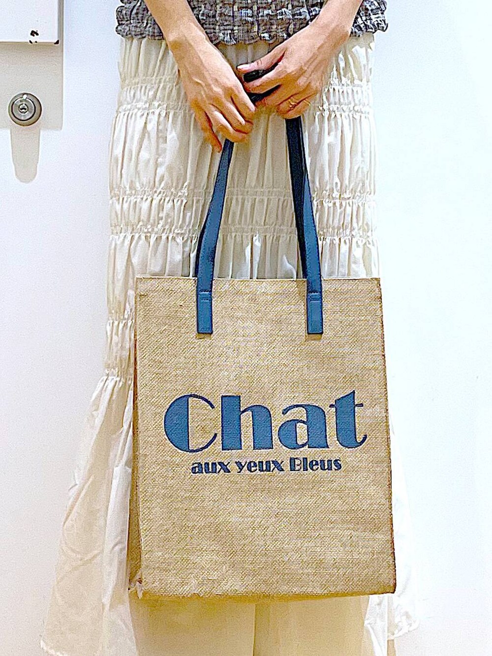 ホワイト系のサンダル、ブルー系のトートバッグ、その他のTシャツ/カットソーを着用したレディースの夏コーディネートの7枚目の写真