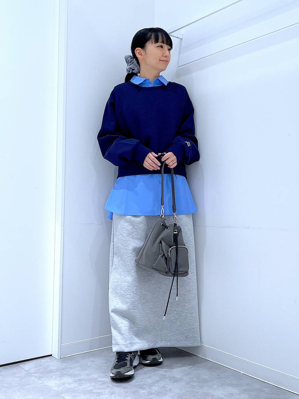 グレー系のショルダーバッグ、グレー系のスカート、ブルー系のシャツ/ブラウスを着用したレディースの春コーディネートの2枚目の写真