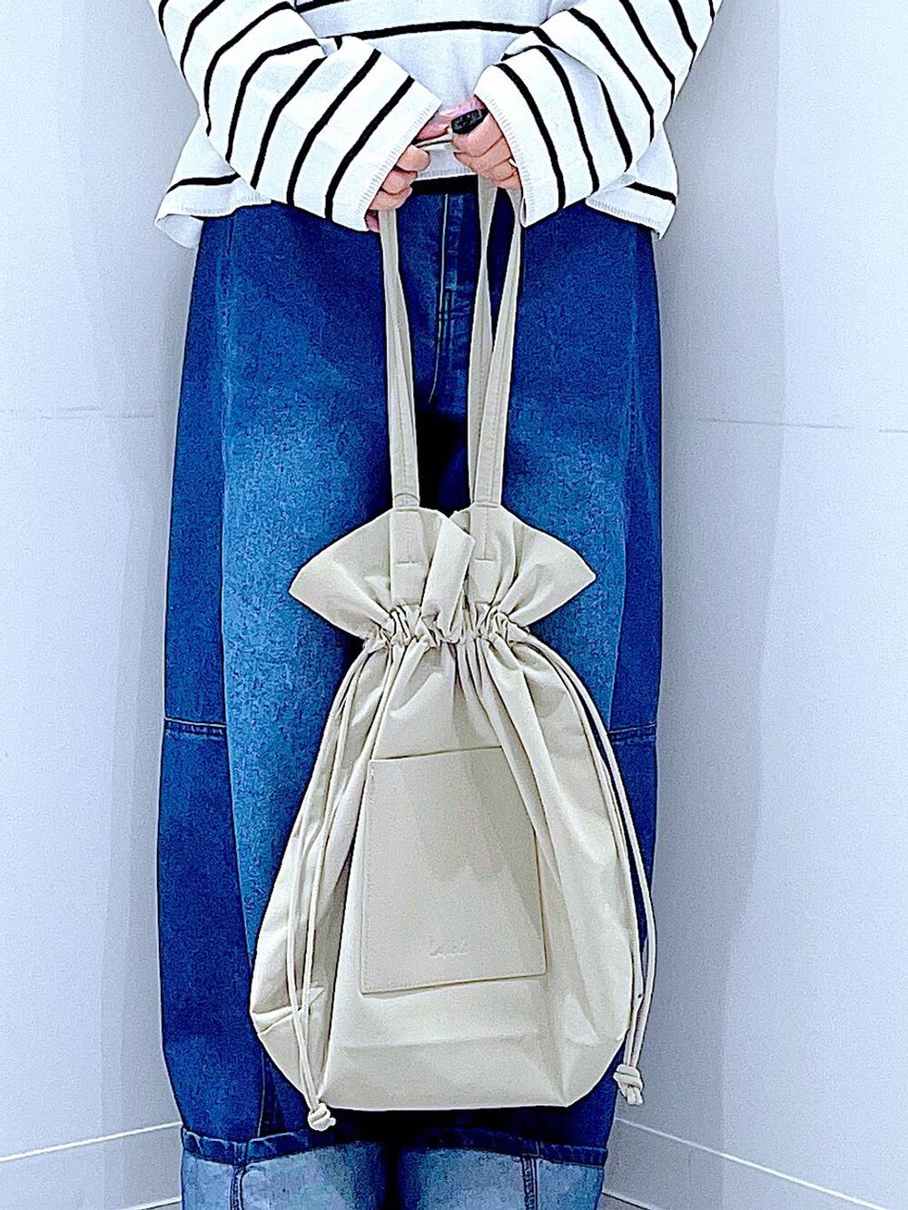 ブラック系のTシャツ/カットソー、ベージュ系のトートバッグ、ブルー系のデニムパンツを着用したレディースの冬コーディネートの9枚目の写真