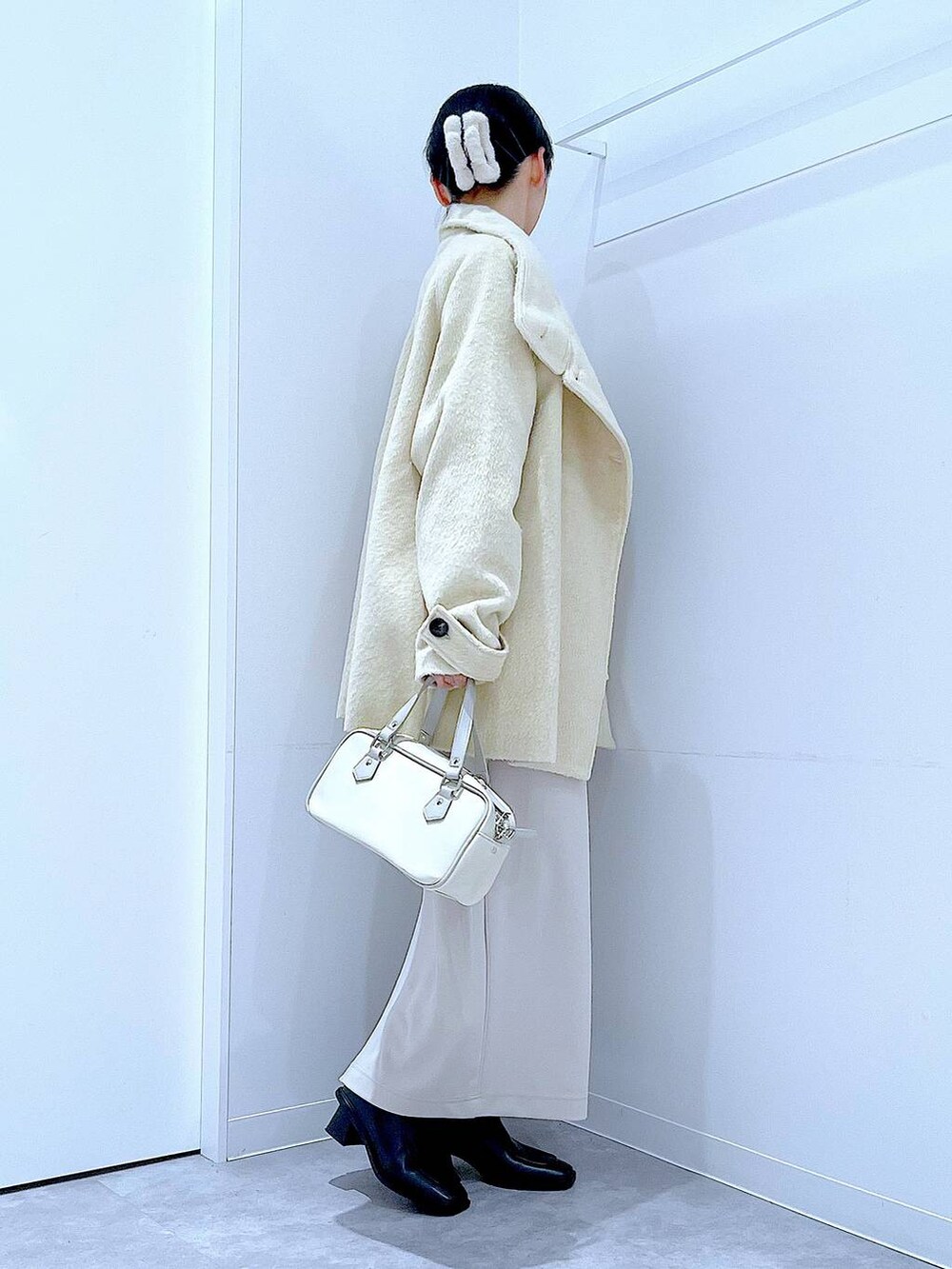 ベージュ系のスカート、ベージュ系のステンカラーコート、ブラック系のブーツを着用したレディースの冬コーディネートの4枚目の写真