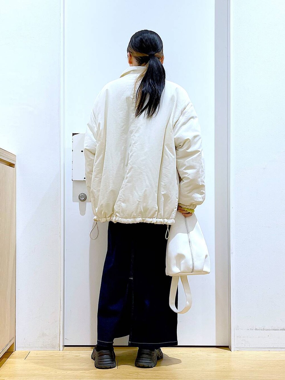 グリーン系のニット/セーター、ブルー系のジャンパースカート、ホワイト系のボディバッグ/ウエストポーチを着用したレディースの冬コーディネートの5枚目の写真