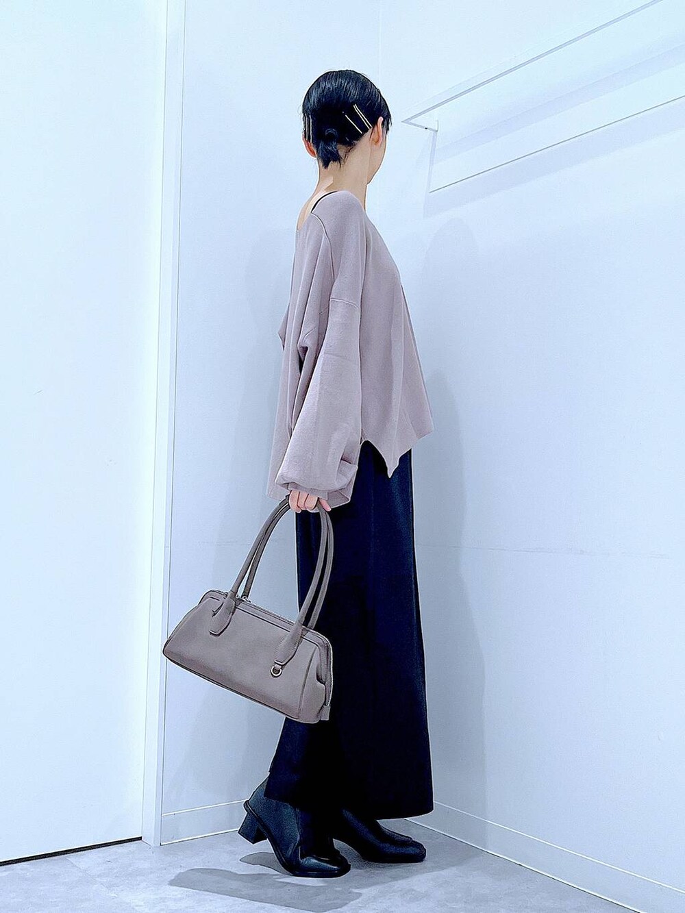 ブラック系のスカート、ブラウン系のニット/セーター、ブラック系のブーツを着用したレディースの秋コーディネートの4枚目の写真