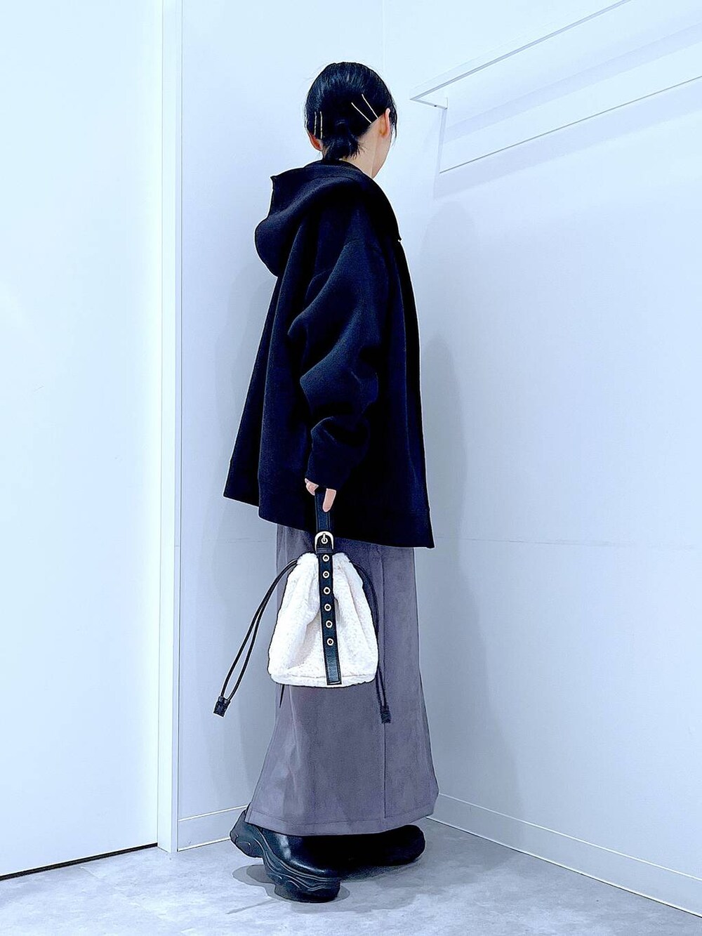 ホワイト系のハンドバッグ、ブラック系のブーツ、グレー系のスカートを着用したレディースの冬コーディネートの4枚目の写真