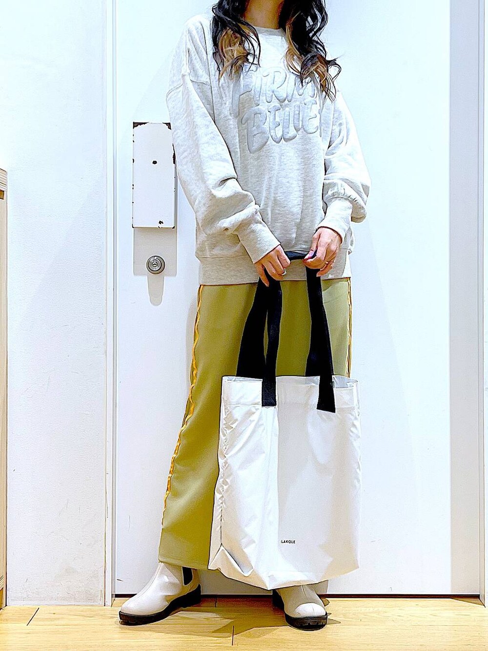 ベージュ系のスウェット、ベージュ系のブーツ、ホワイト系のトートバッグを着用したレディースの冬コーディネートの6枚目の写真