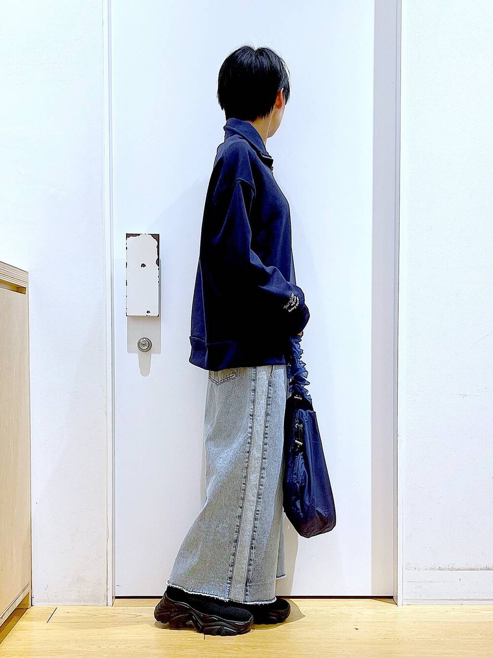 ブルー系のショルダーバッグ、ブラック系のブーツ、ブルー系のデニムスカートを着用したレディースの春コーディネートの4枚目の写真