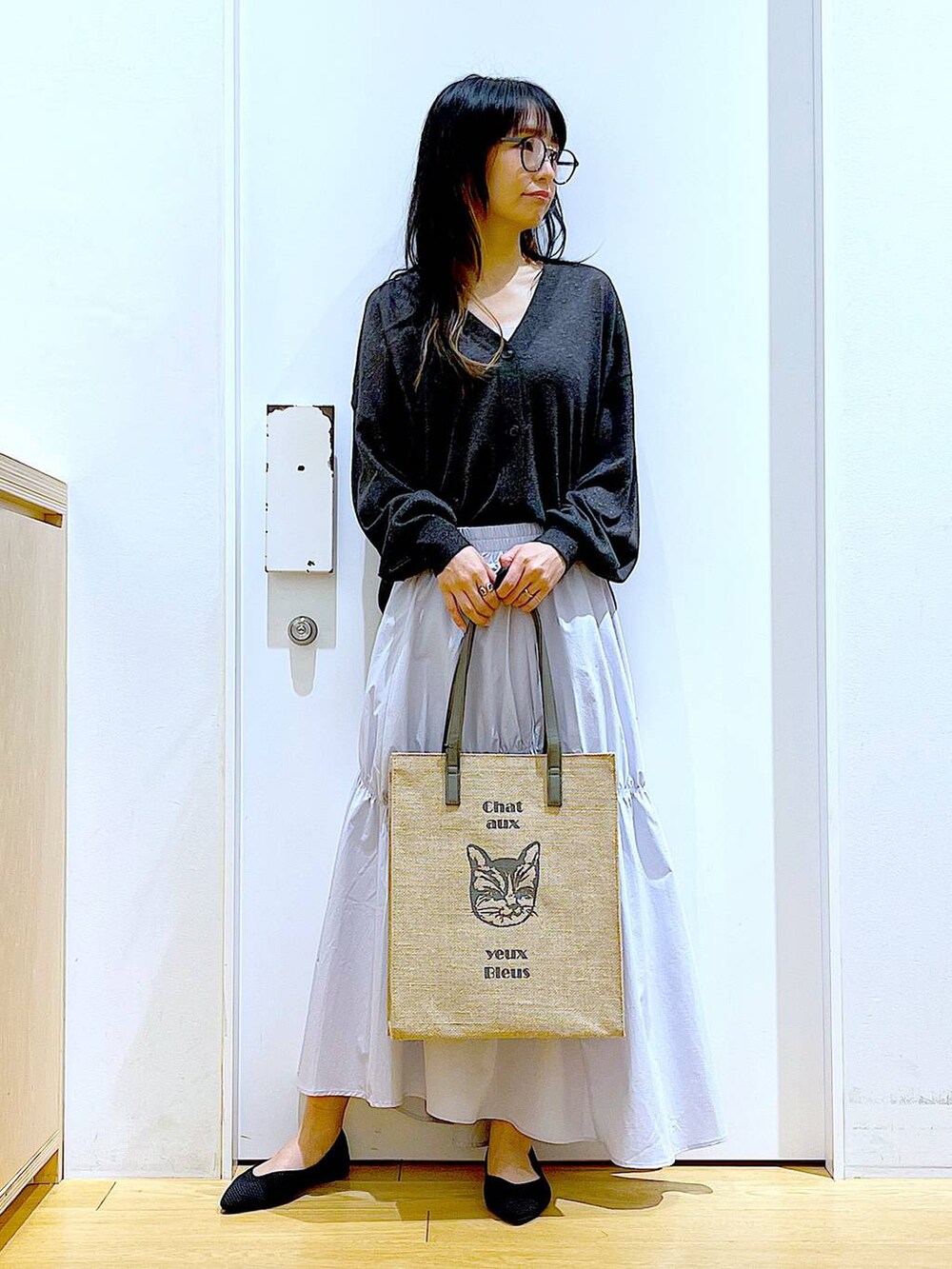 ブルー系のスカート、グレー系のカーディガン/ボレロ、ブラック系のパンプスを着用したレディースの春コーディネートの2枚目の写真