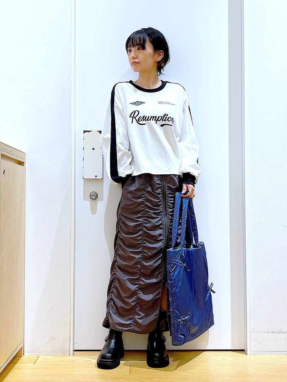 ブラック系のブーツ、ブルー系のトートバッグ、ホワイト系のTシャツ/カットソーを着用したレディースの秋コーディネートの2枚目の写真