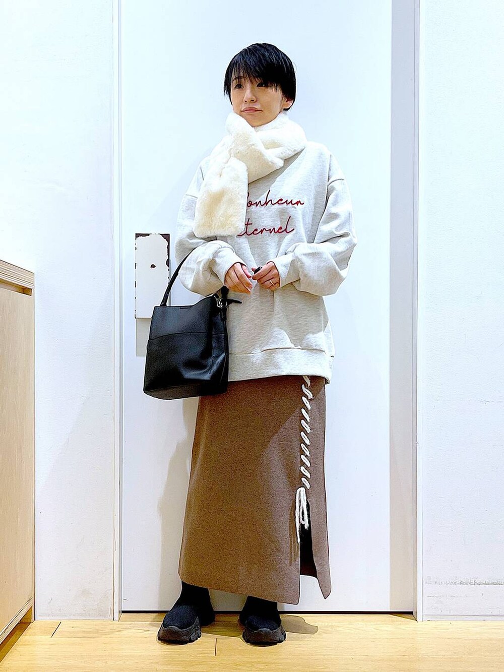 ブラック系のショルダーバッグ、ブラック系のブーツ、ブラウン系のスカートを着用したレディースの冬コーディネートの2枚目の写真