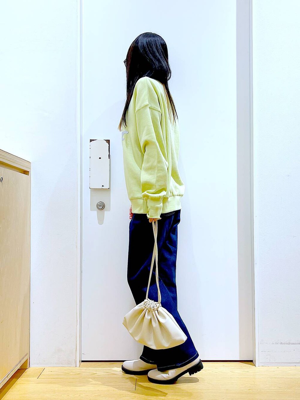 ブルー系のデニムパンツ、イエロー系のスウェット、ベージュ系のブーツを着用したレディースの冬コーディネートの3枚目の写真