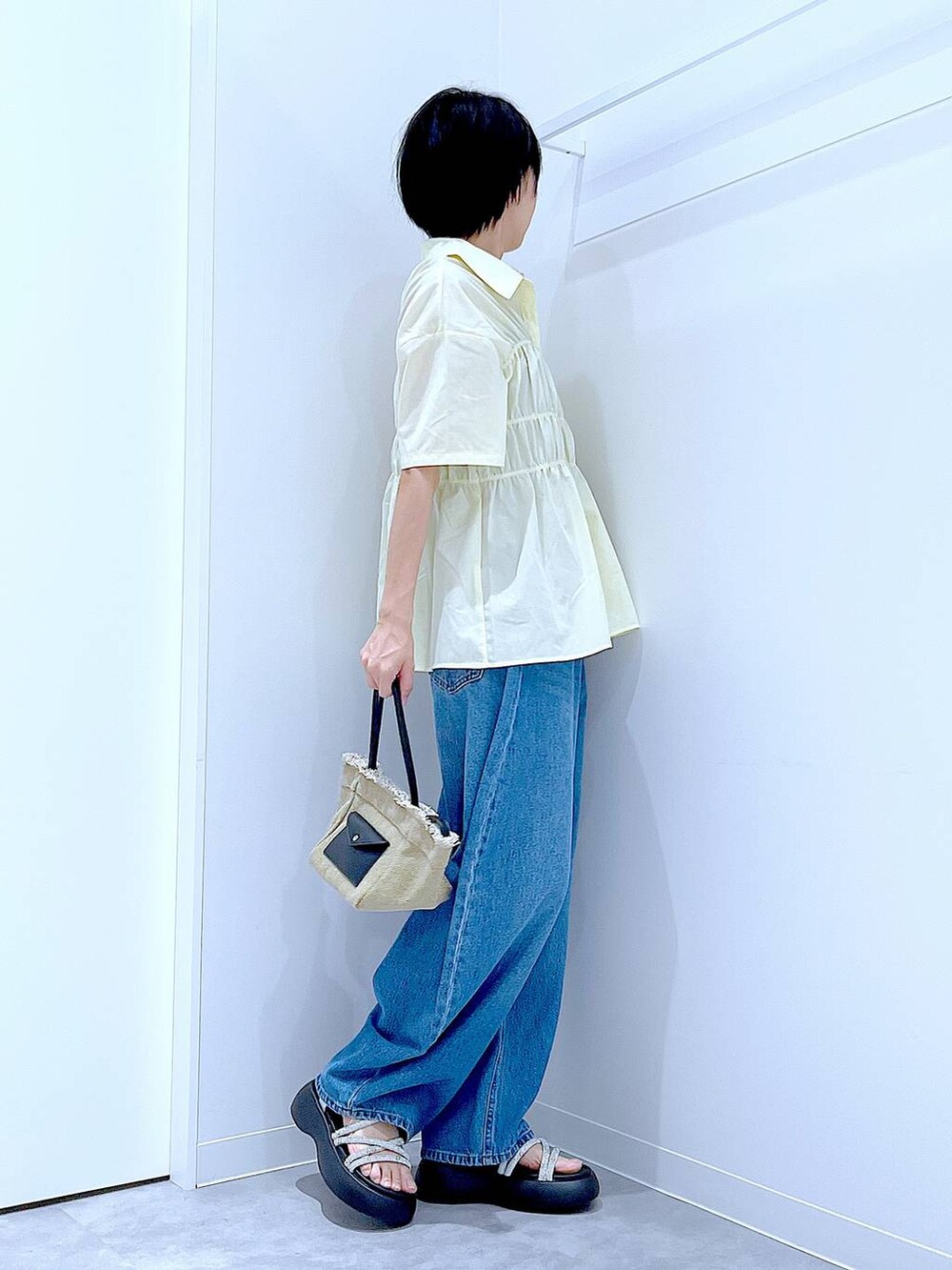 ブルー系のデニムパンツ、ベージュ系のショルダーバッグ、シルバー系のサンダルを着用したレディースの夏コーディネートの4枚目の写真