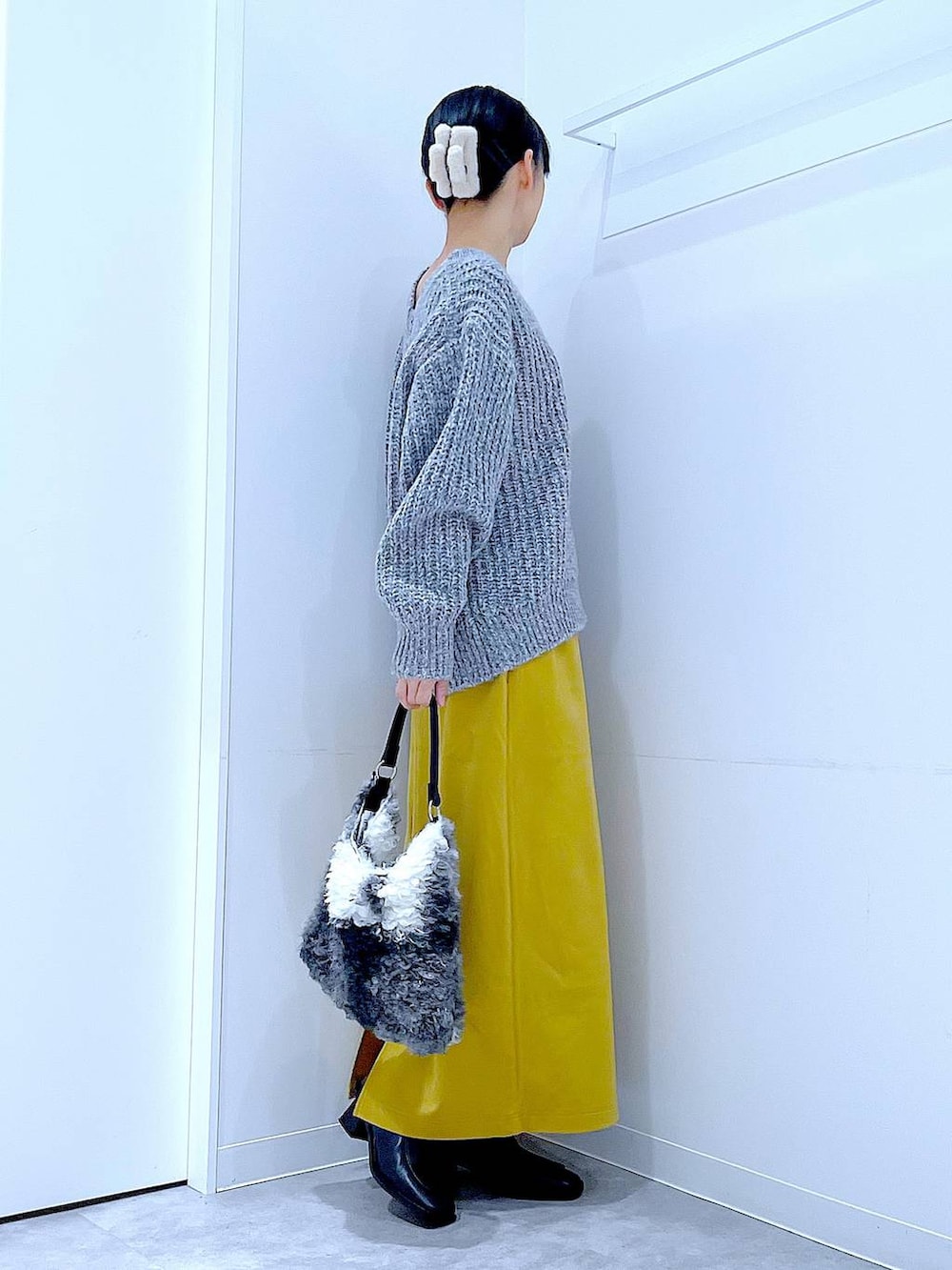 グレー系のニット/セーター、イエロー系のスカート、ブラック系のブーツを着用したレディースの冬コーディネートの4枚目の写真