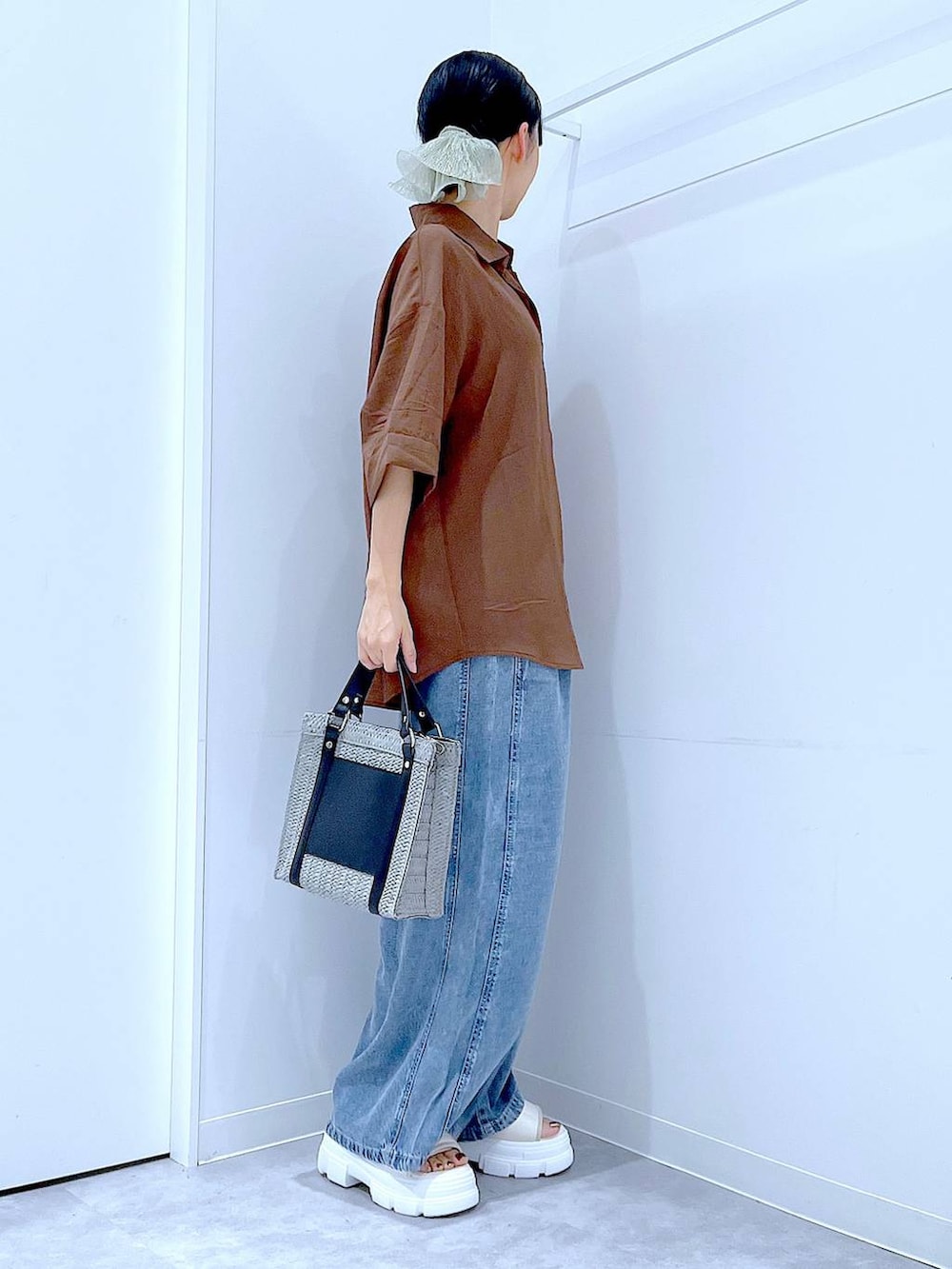 グレー系のショルダーバッグ、ホワイト系のサンダル、ブルー系のデニムパンツを着用したレディースの夏コーディネートの4枚目の写真