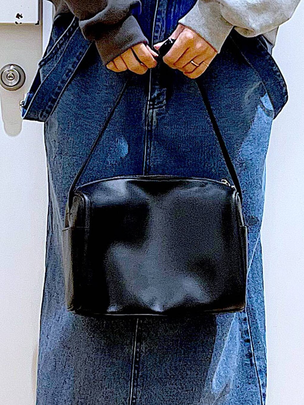 ブラック系のショルダーバッグ、ブラック系のブーツ、ブルー系のジャンパースカートを着用したレディースの春コーディネートの9枚目の写真