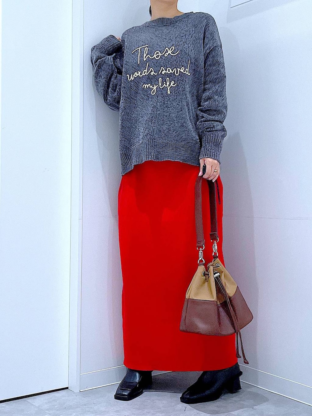 ベージュ系のショルダーバッグ、ブラック系のブーツ、グレー系のニット/セーターを着用したレディースの冬コーディネートの6枚目の写真