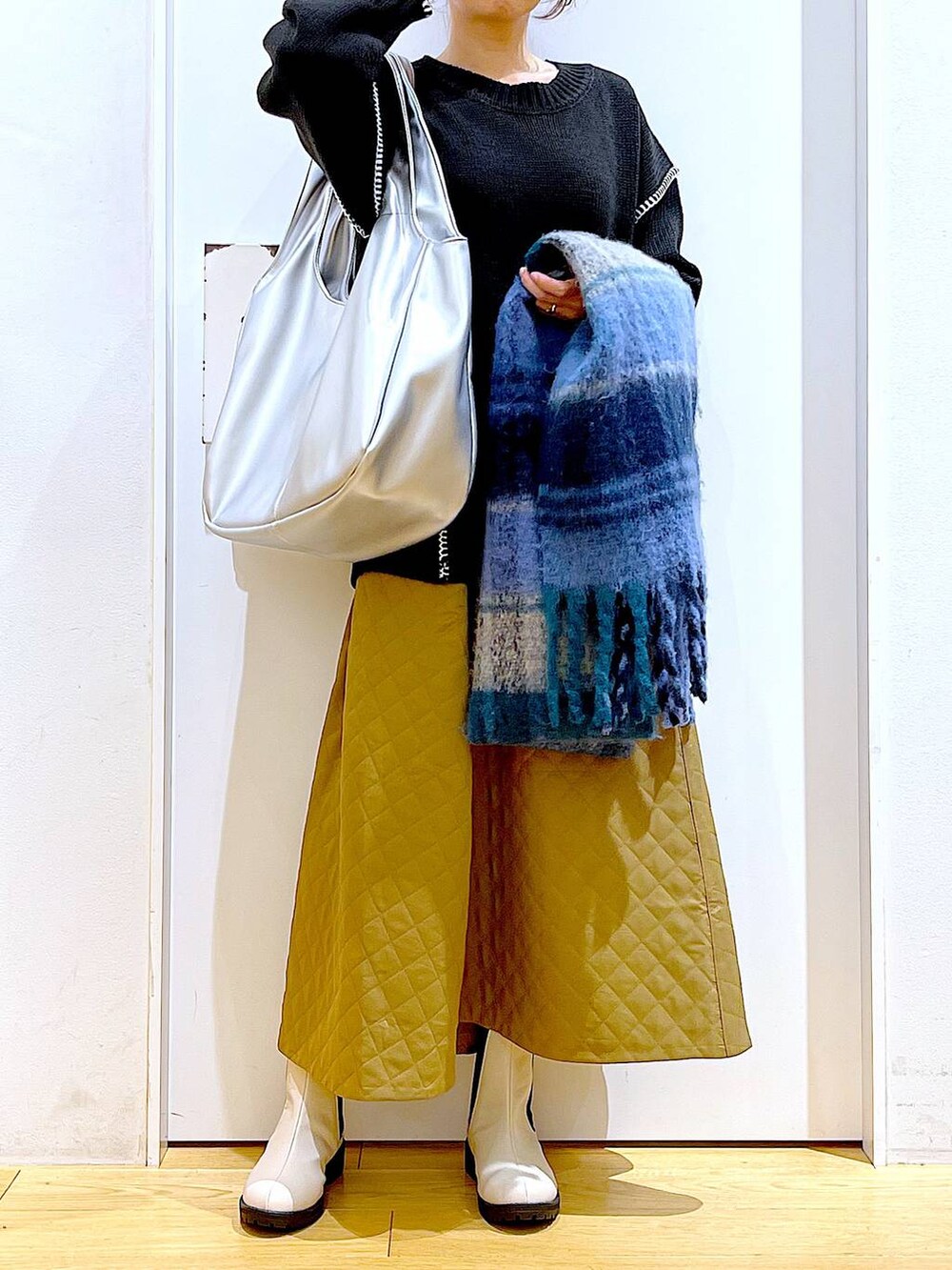 シルバー系のトートバッグ、ベージュ系のブーツ、ブラック系のニット/セーターを着用したレディースの冬コーディネートの6枚目の写真