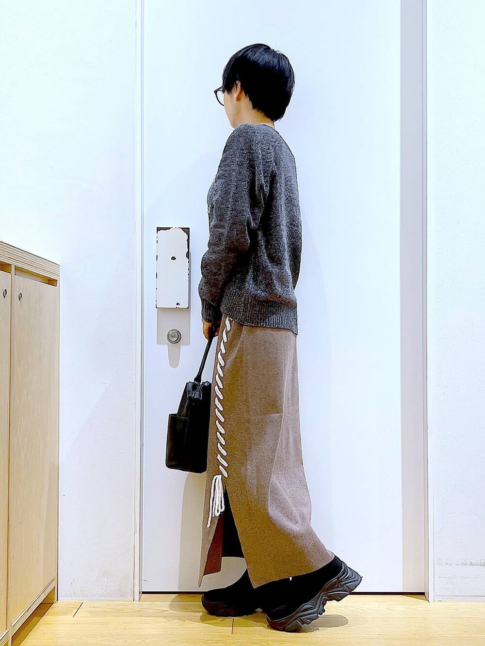 ブラック系のブーツ、ブラック系のショルダーバッグ、ブラウン系のスカートを着用したレディースの冬コーディネートの3枚目の写真