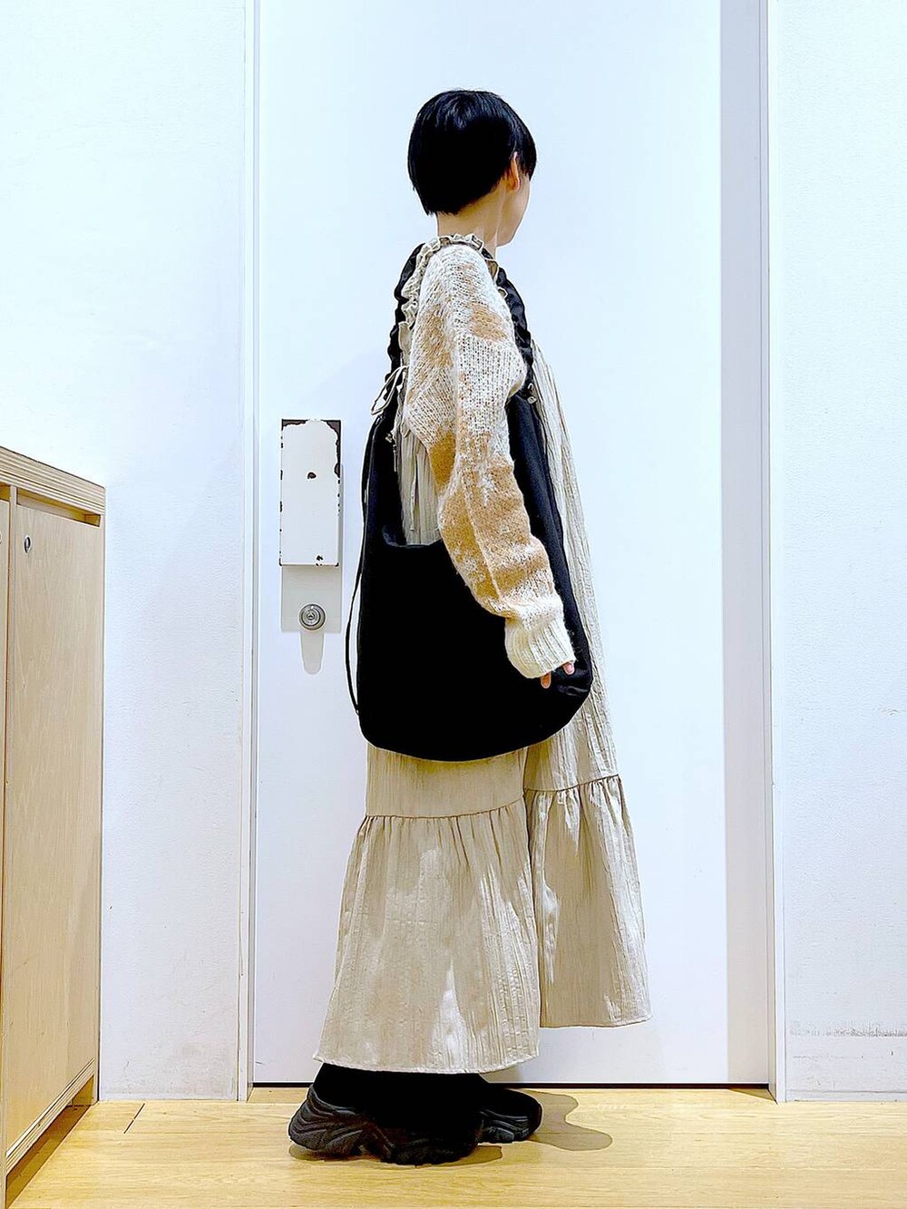 ブラック系のショルダーバッグ、ブラック系のブーツ、ベージュ系のワンピースを着用したレディースの冬コーディネートの4枚目の写真