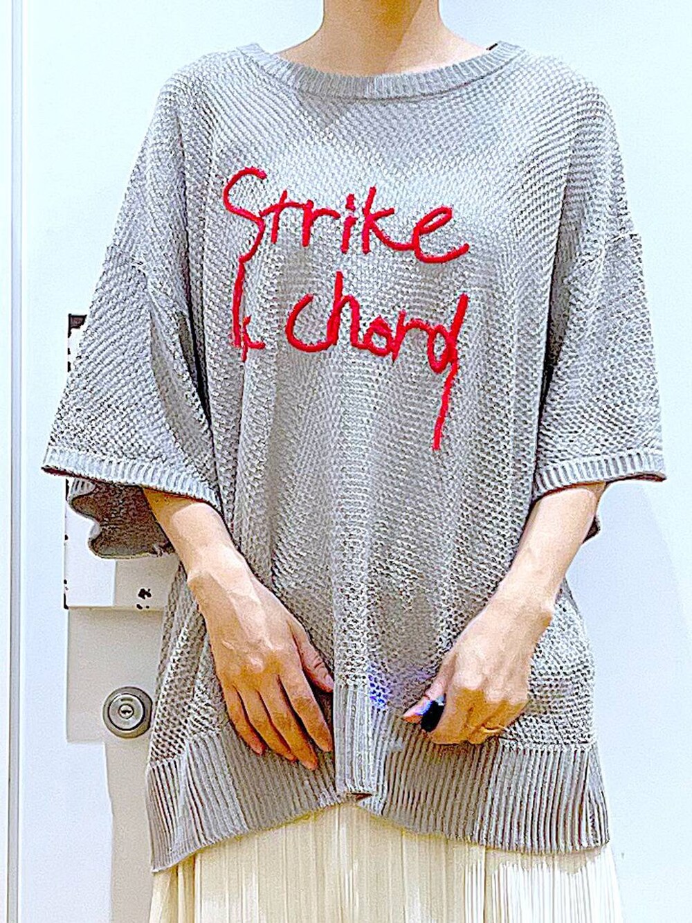 ブラック系のパンプス、ホワイト系のスカート、グレー系のニット/セーターを着用したレディースの春コーディネートの7枚目の写真