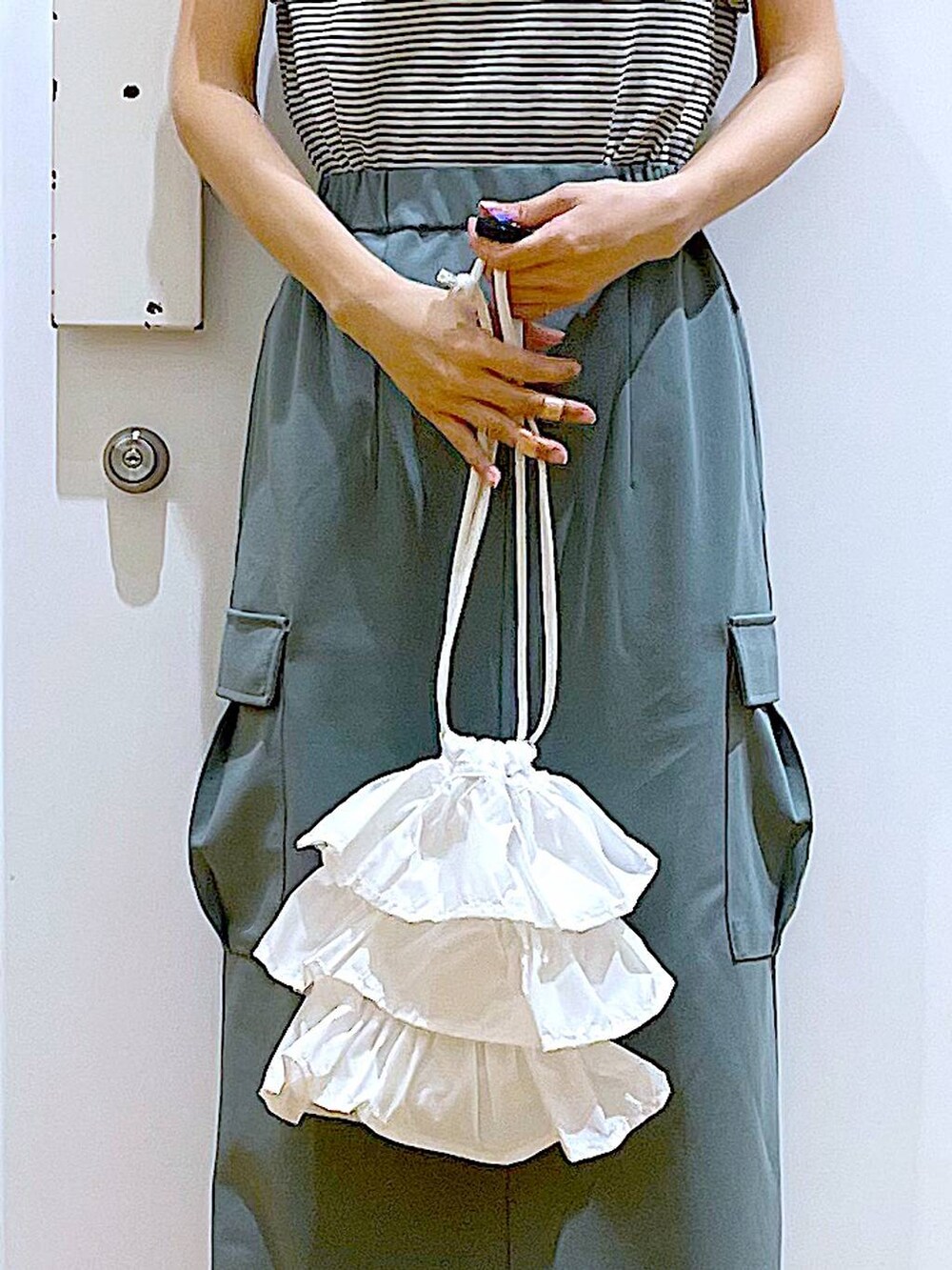 ホワイト系のショルダーバッグ、ホワイト系のパンプス、グリーン系のスカートを着用したレディースの春コーディネートの9枚目の写真