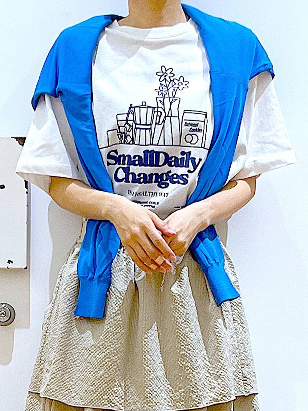 シルバー系のショルダーバッグ、ブルー系のカーディガン/ボレロ、ホワイト系のパンプスを着用したレディースの春コーディネートの7枚目の写真