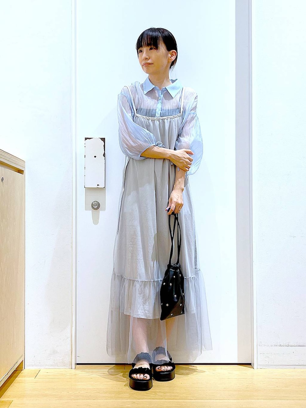 ブラック系のサンダル、ブラック系のショルダーバッグ、ブルー系のシャツ/ブラウスを着用したレディースの夏コーディネートの2枚目の写真