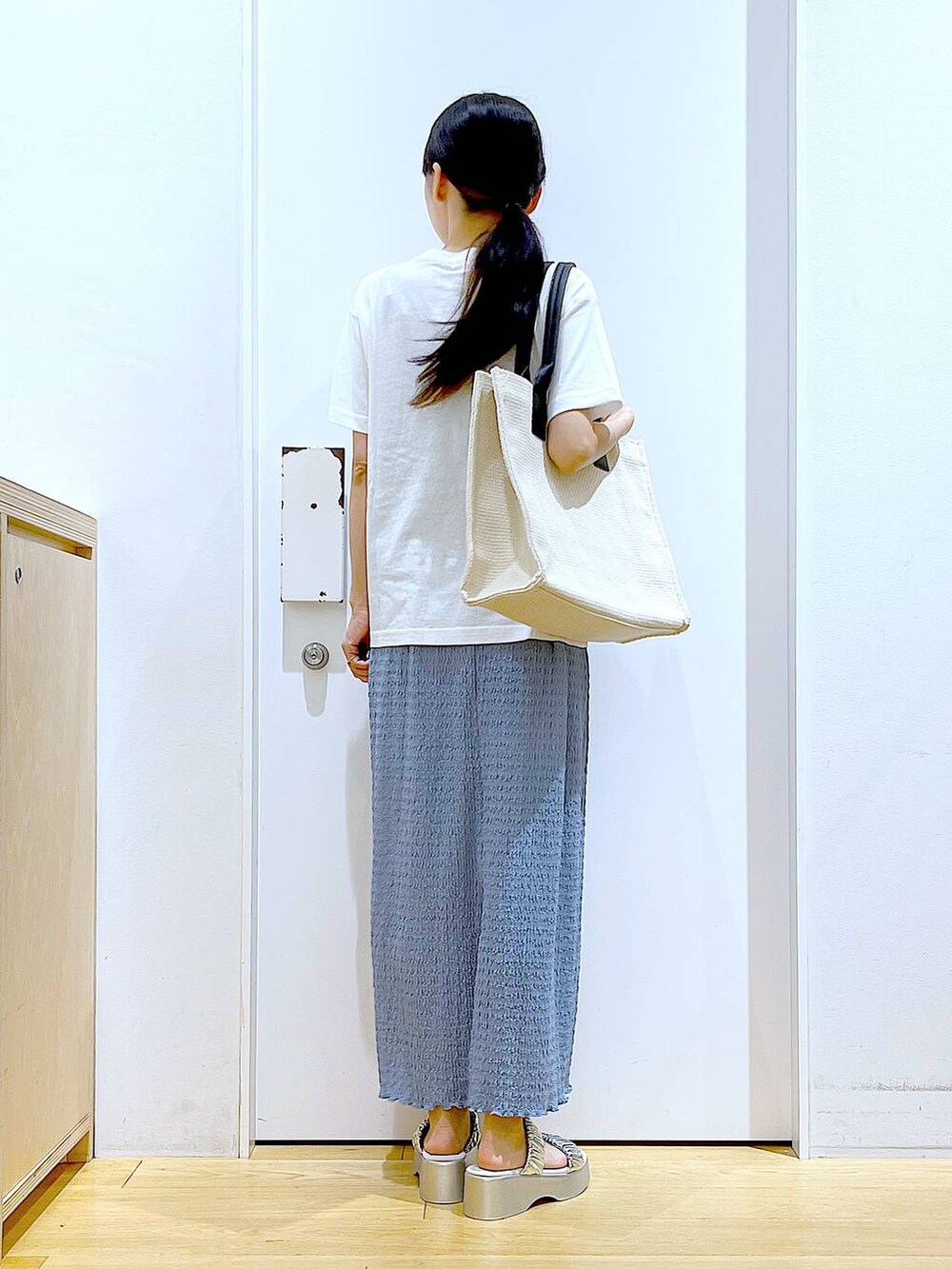 シルバー系のサンダル、ブルー系のスカート、ホワイト系のトートバッグを着用したレディースの夏コーディネートの5枚目の写真