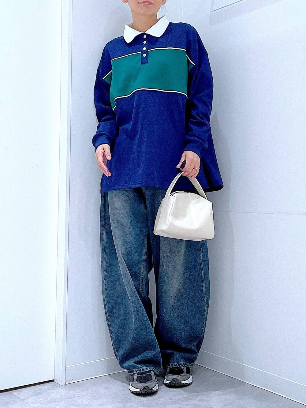 ブルー系のデニムパンツ、ホワイト系のショルダーバッグ、ブルー系のポロシャツを着用したレディースの冬コーディネートの6枚目の写真