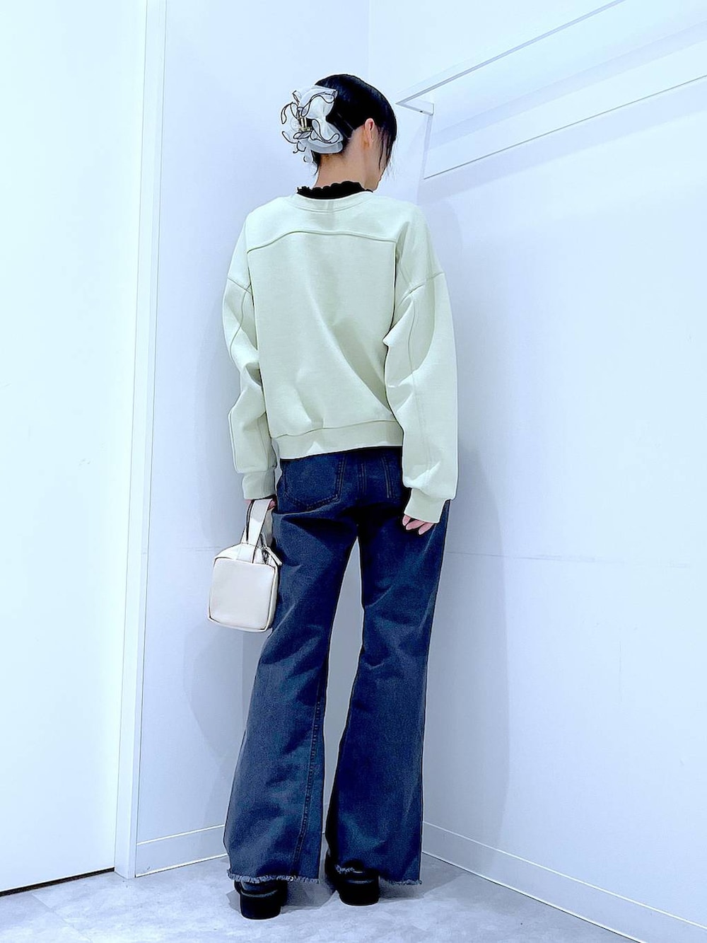 ホワイト系のショルダーバッグ、グリーン系のスウェット、ブラック系のデニムパンツを着用したレディースの春コーディネートの5枚目の写真