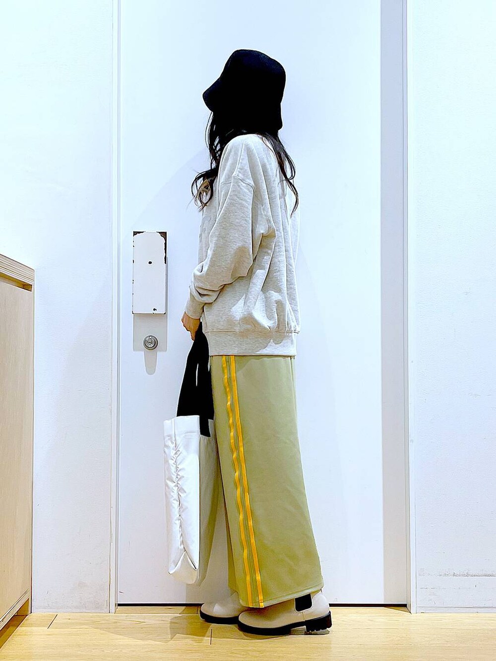 ベージュ系のスウェット、ベージュ系のブーツ、ホワイト系のトートバッグを着用したレディースの冬コーディネートの3枚目の写真