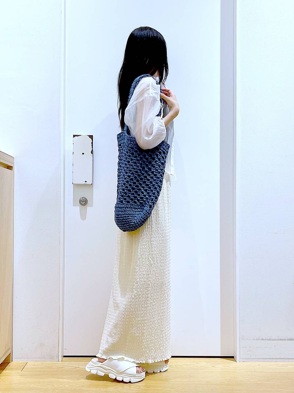 ホワイト系のサンダル、ブラック系のニット/セーター、ブルー系のトートバッグを着用したレディースの夏コーディネートの4枚目の写真