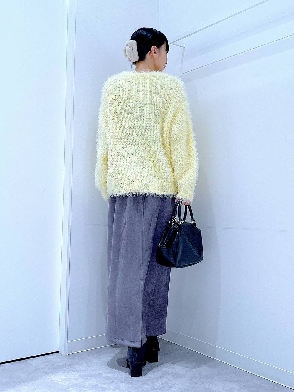 ブラック系のブーツ、イエロー系のニット/セーター、ブラック系のショルダーバッグを着用したレディースの冬コーディネートの5枚目の写真