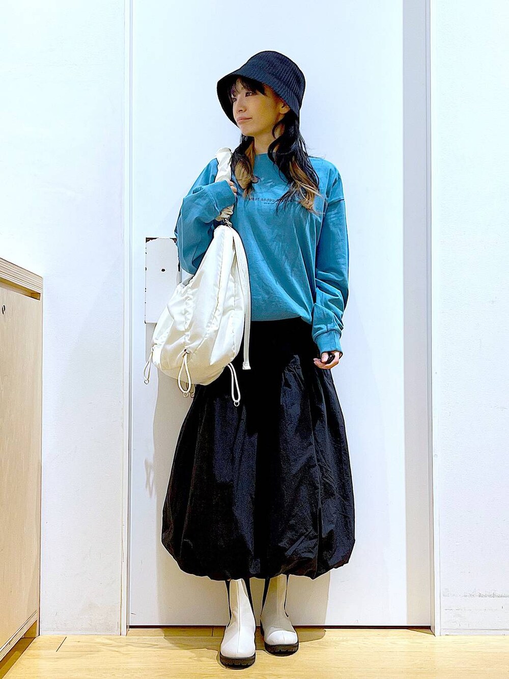 グリーン系のTシャツ/カットソー、ベージュ系のブーツ、ホワイト系のショルダーバッグを着用したレディースの春コーディネートの2枚目の写真