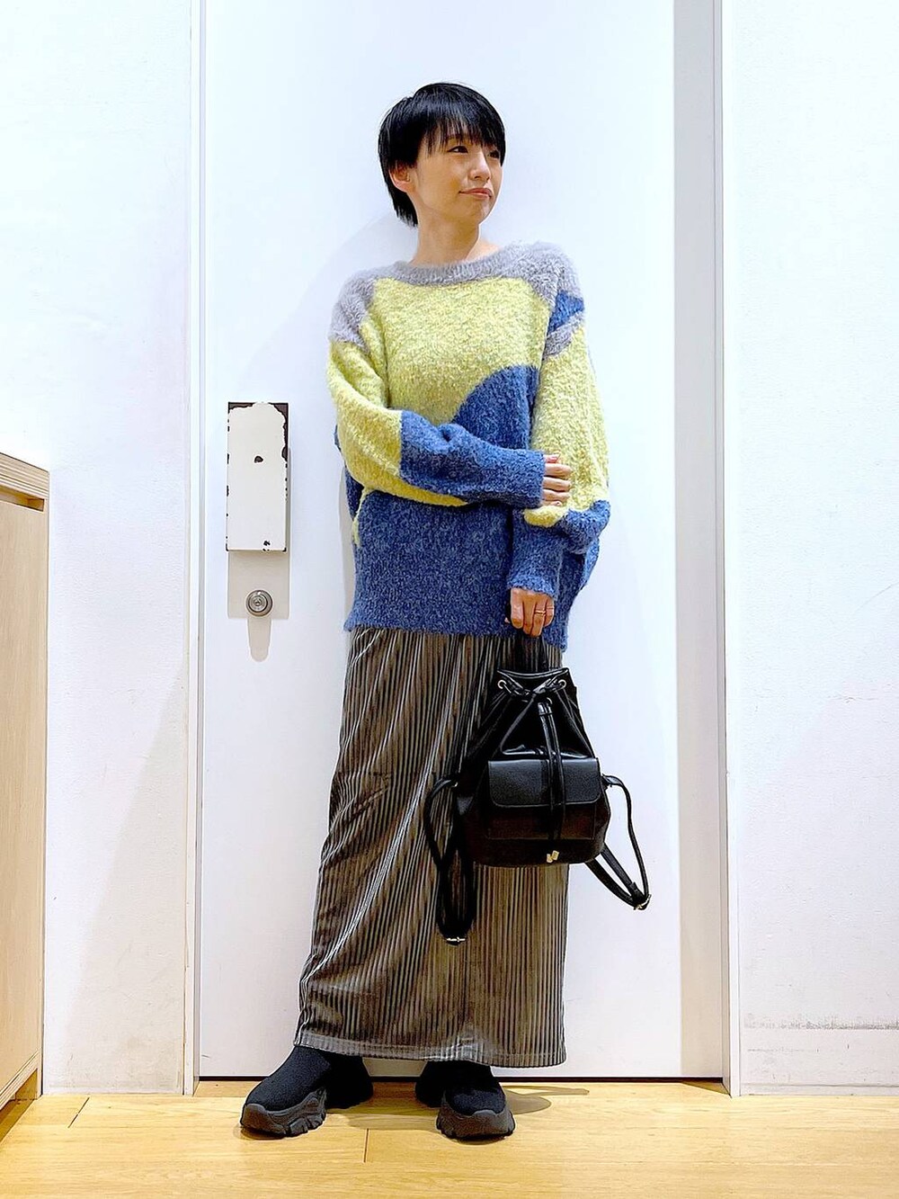 ブラック系のバックパック/リュック、グレー系のスカート、ブラック系のブーツを着用したレディースの冬コーディネートの2枚目の写真