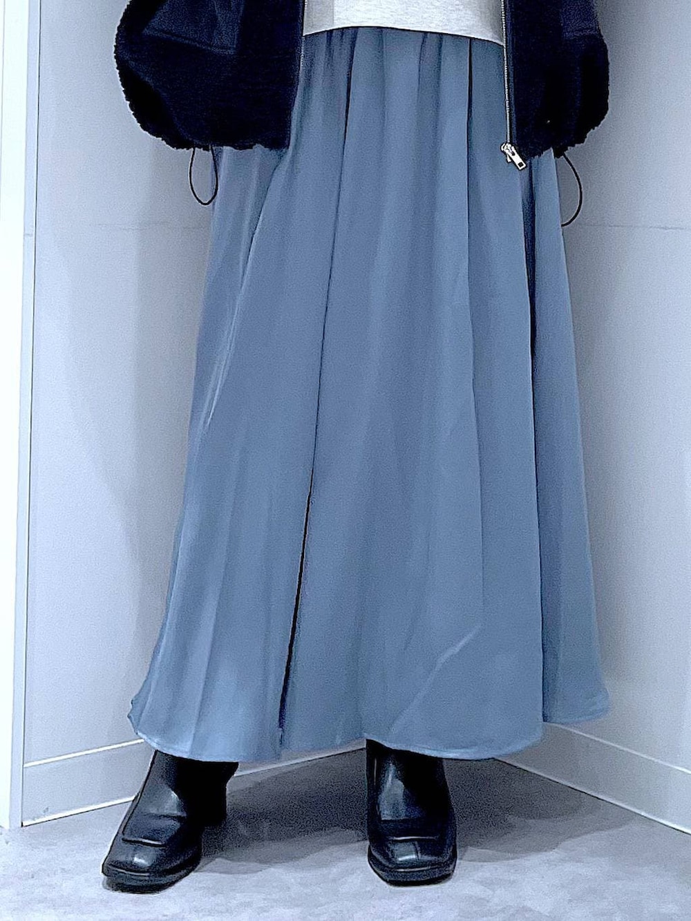 ブラック系のブルゾン、ブラック系のブーツ、ブルー系のスカートを着用したレディースの冬コーディネートの8枚目の写真