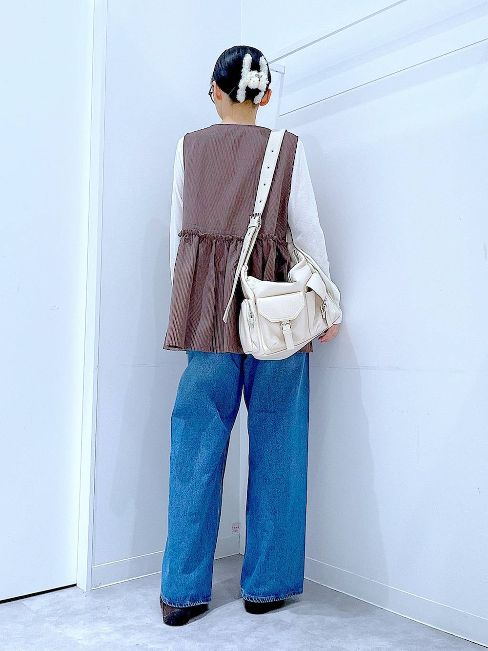 ブルー系のデニムパンツ、ブラウン系のベスト、ホワイト系のTシャツ/カットソーを着用したレディースの秋コーディネートの5枚目の写真