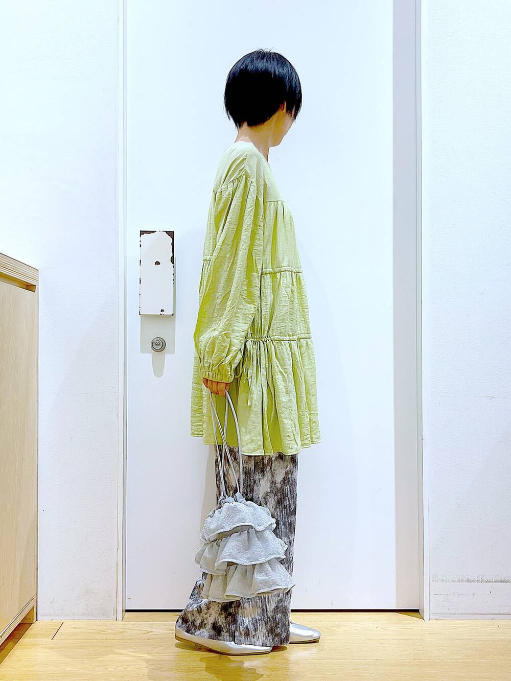 シルバー系のショルダーバッグ、シルバー系のパンプス、グリーン系のチュニックを着用したレディースの春コーディネートの4枚目の写真