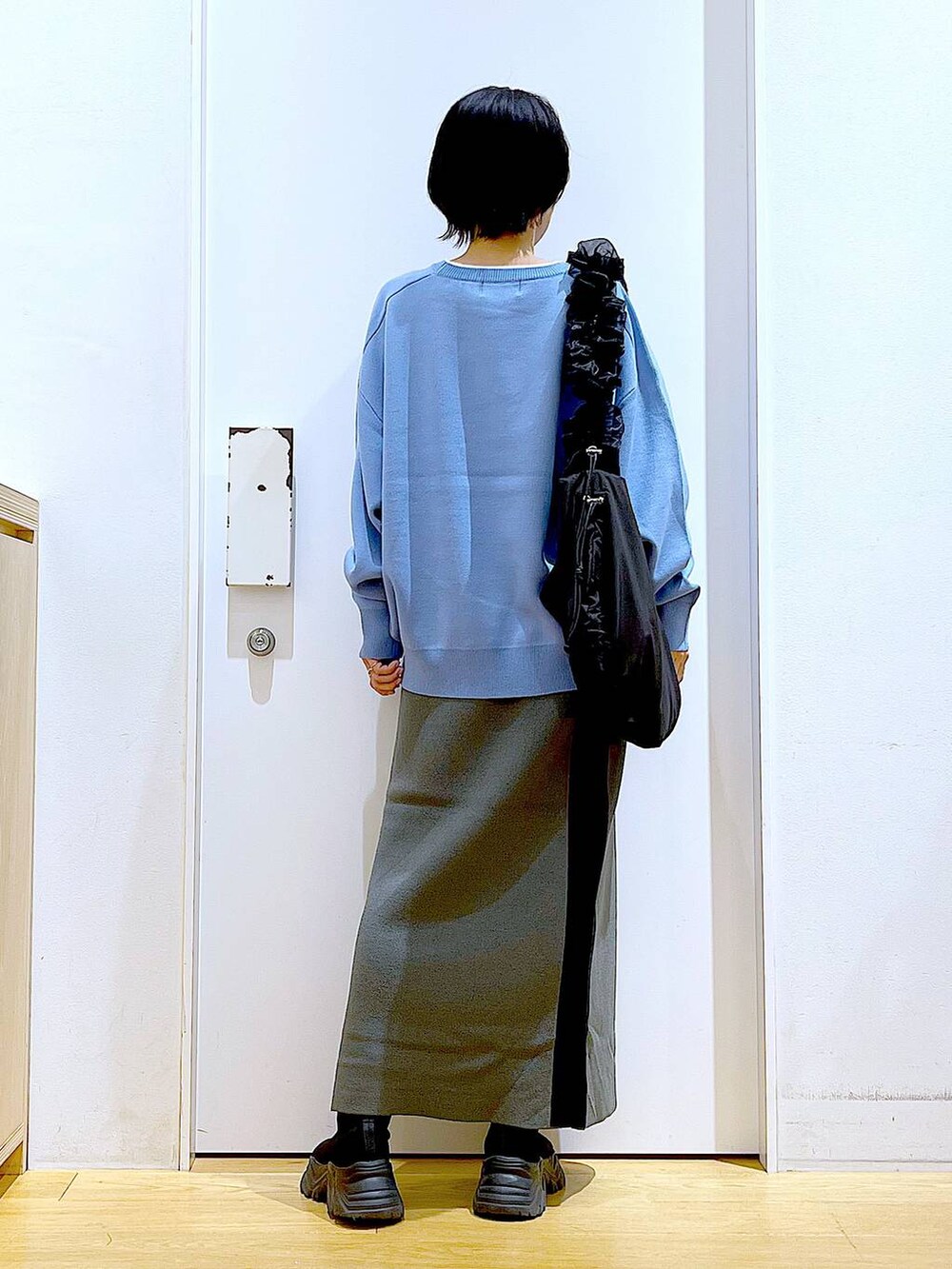 ブルー系のニット/セーター、ブラック系のショルダーバッグ、グレー系のスカートを着用したレディースの冬コーディネートの5枚目の写真