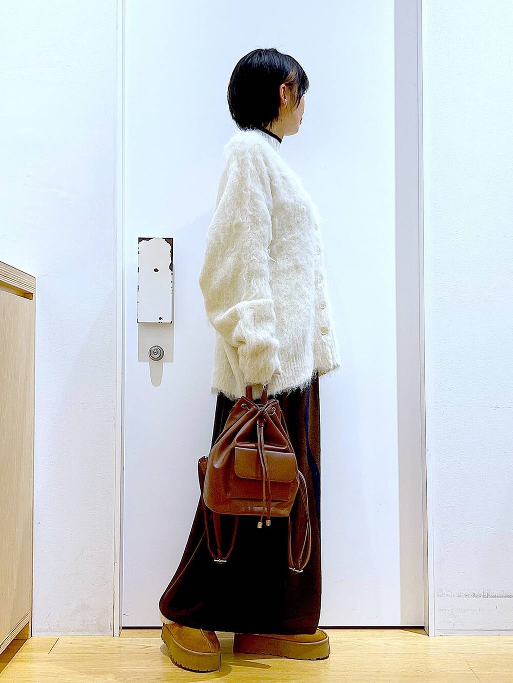 ベージュ系のニット/セーター、ブラウン系のバックパック/リュック、ブラウン系のスカートを着用したレディースの冬コーディネートの4枚目の写真