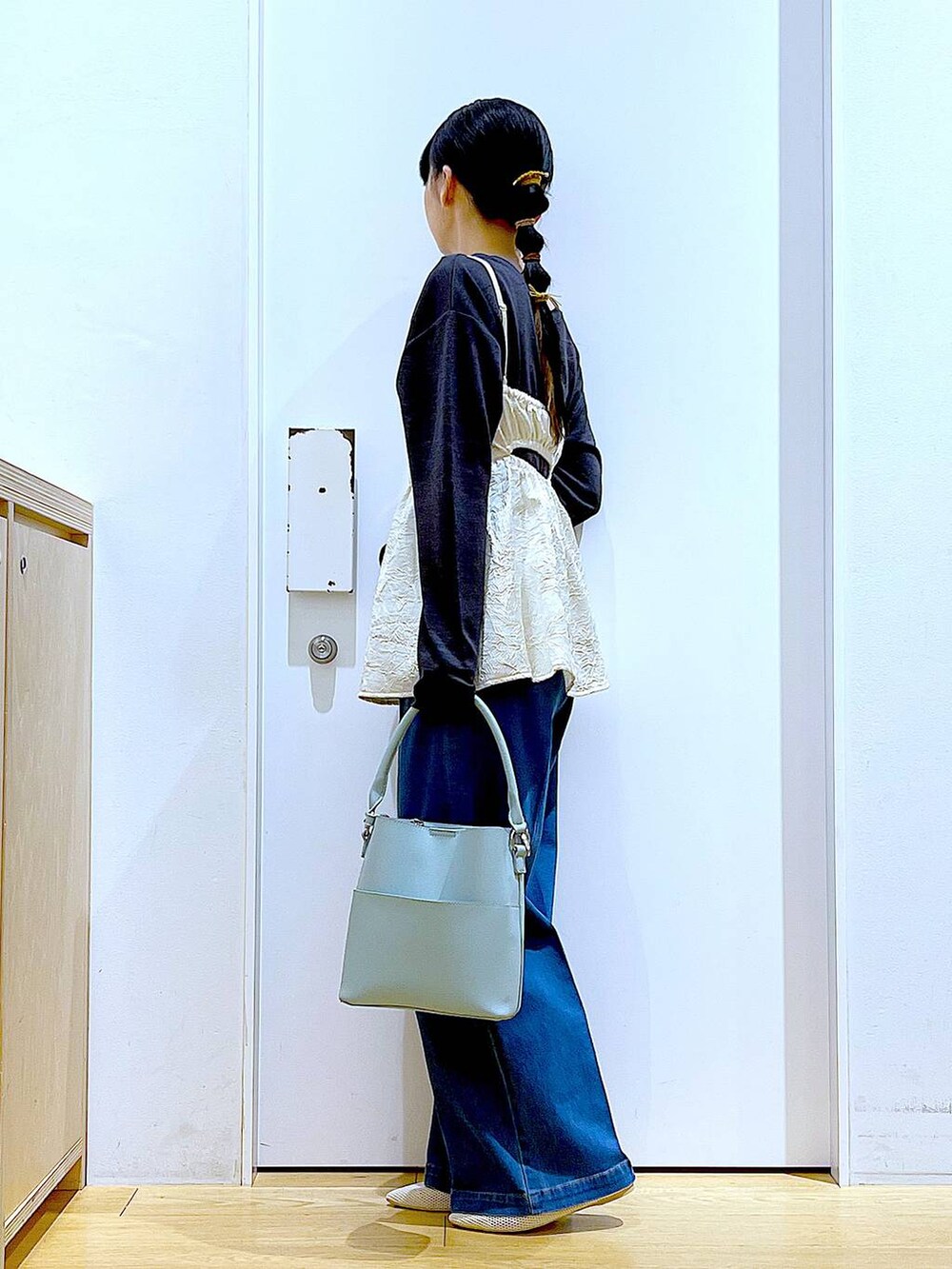 ブルー系のデニムパンツ、ホワイト系のキャミソール、グリーン系のショルダーバッグを着用したレディースの春コーディネートの3枚目の写真