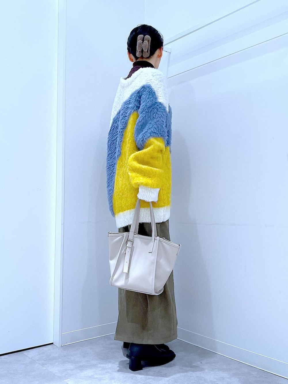 イエロー系のカーディガン/ボレロ、ブラック系のブーツ、グリーン系のスカートを着用したレディースの冬コーディネートの4枚目の写真