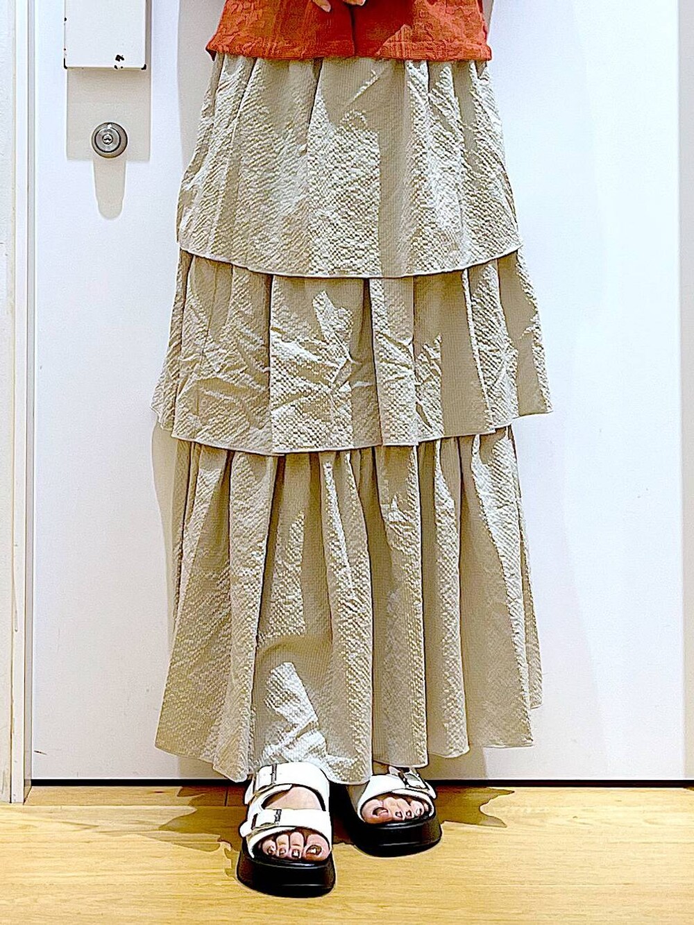 ホワイト系のサンダル、ベージュ系のスカート、レッド系のシャツ/ブラウスを着用したレディースの夏コーディネートの8枚目の写真