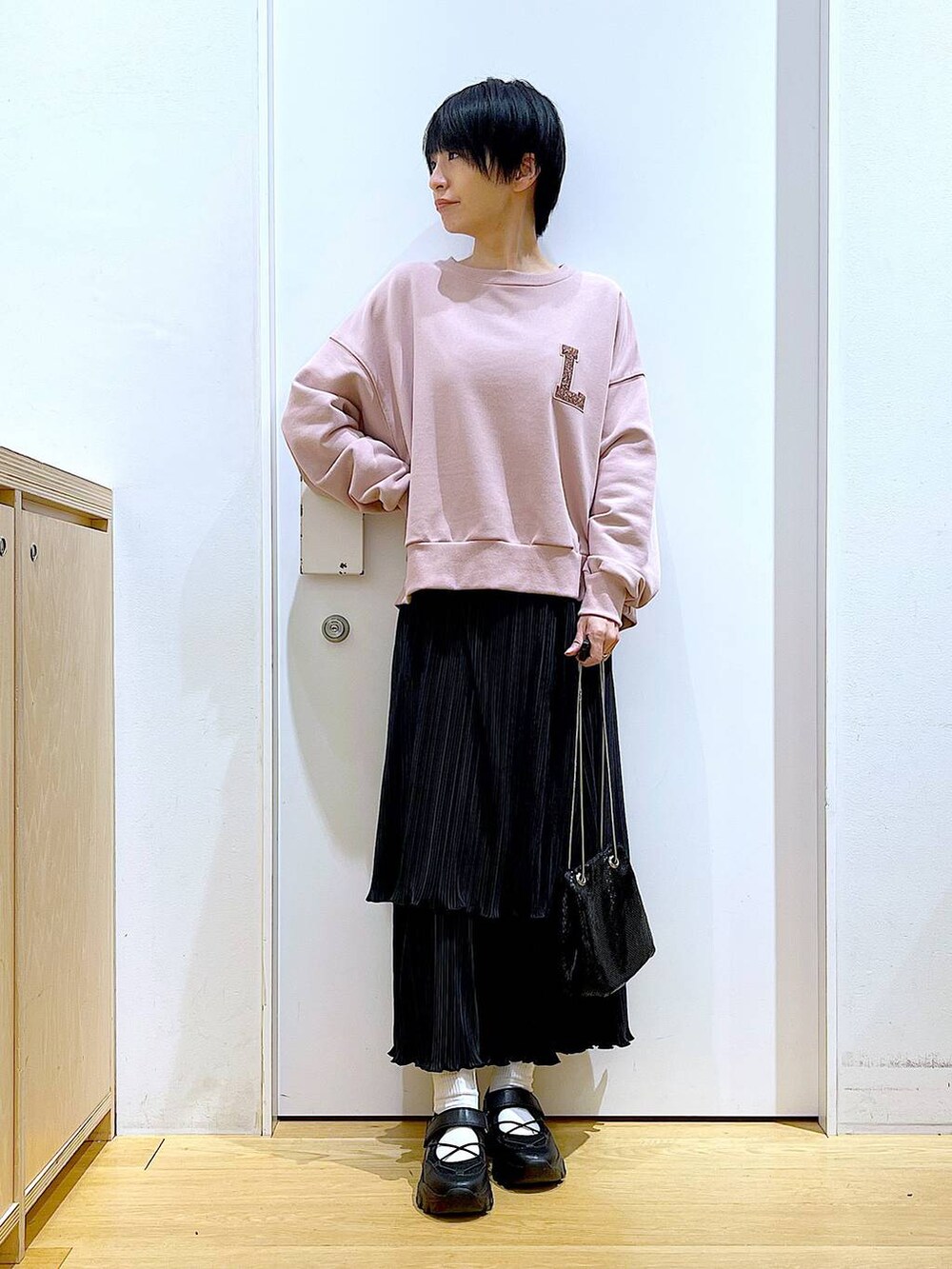 ブラック系のショルダーバッグ、ブラック系のスニーカー、ピンク系のスウェットを着用したレディースの春コーディネートの2枚目の写真
