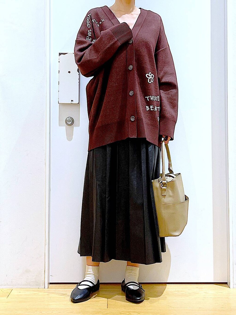 ブラック系のパンプス、ブラック系のスカート、ベージュ系のショルダーバッグを着用したレディースの秋コーディネートの6枚目の写真