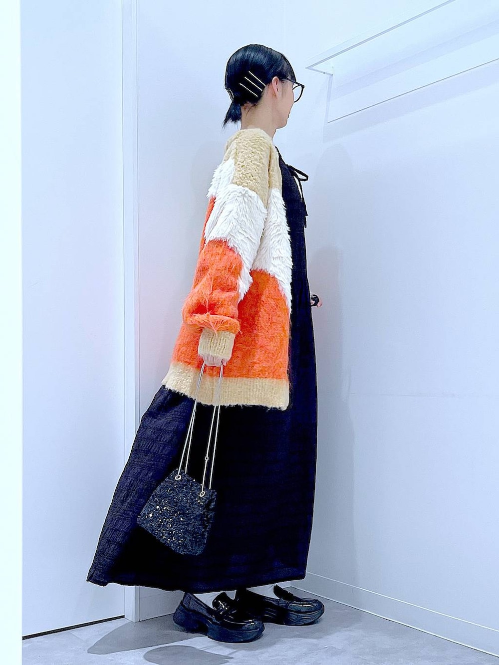 ブラック系のショルダーバッグ、ブラック系のローファー、オレンジ系のカーディガン/ボレロを着用したレディースの秋コーディネートの4枚目の写真