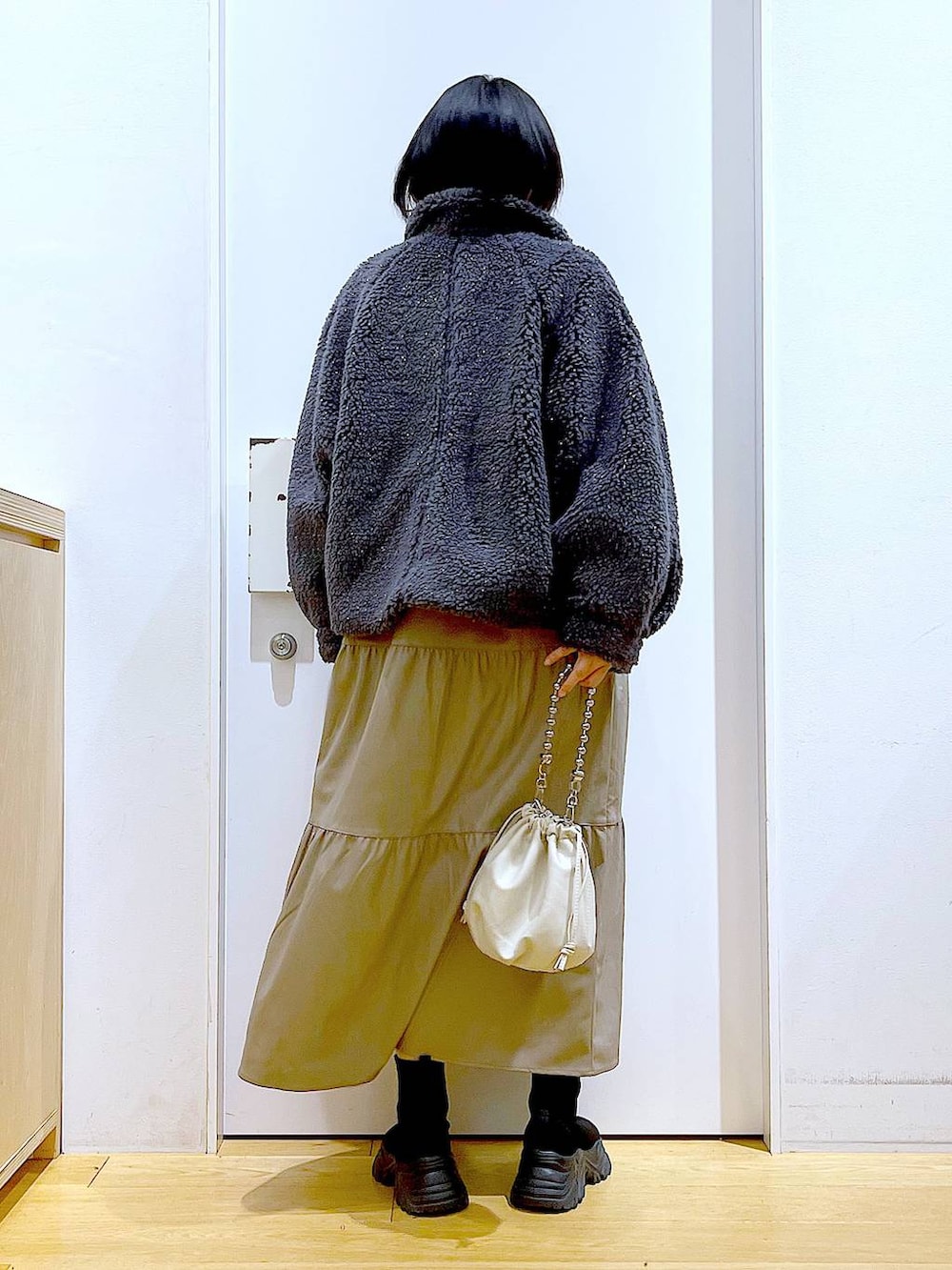 ベージュ系のショルダーバッグ、ブラック系のブーツ、ブラウン系のワンピースを着用したレディースの冬コーディネートの5枚目の写真