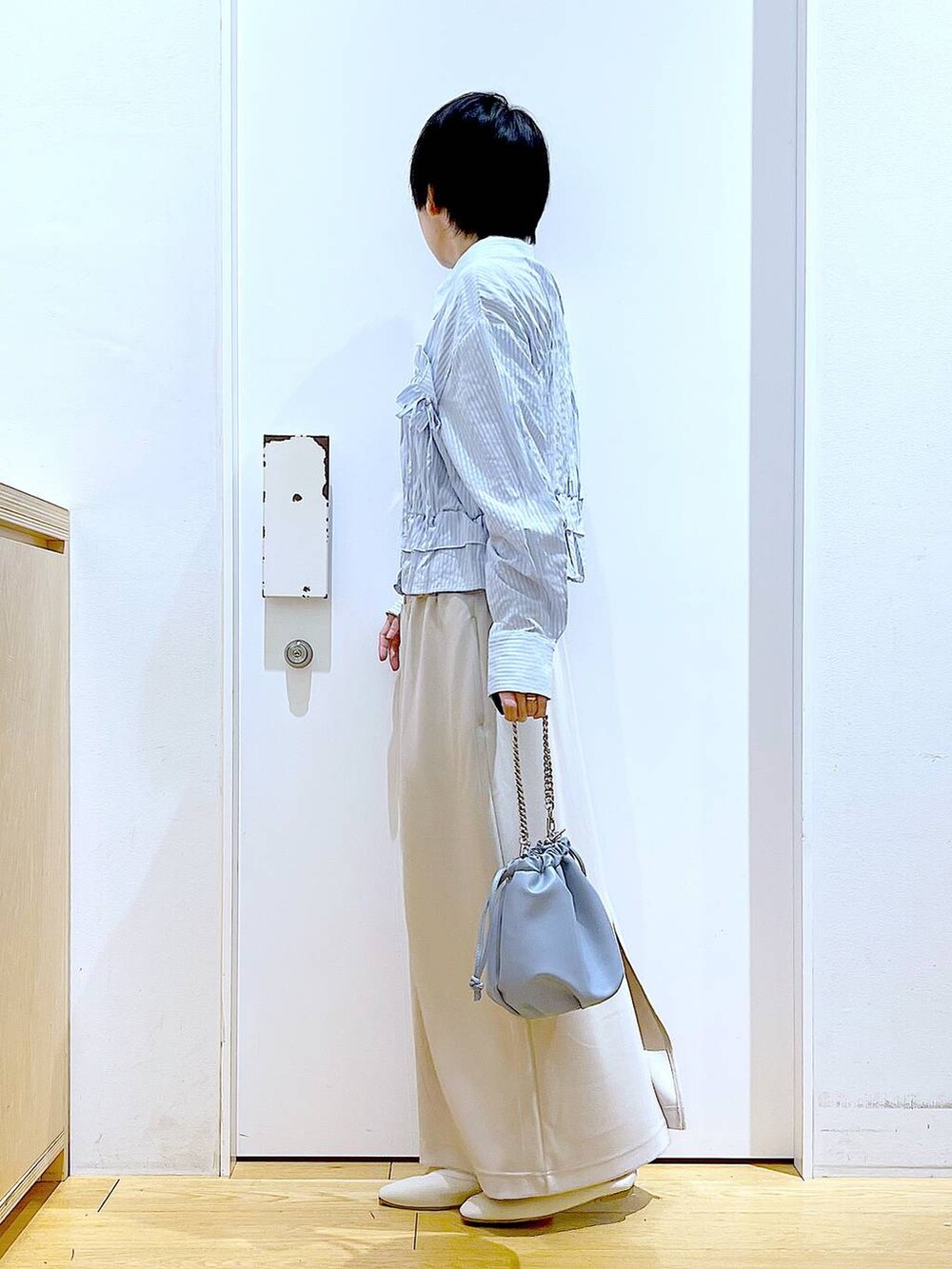 ブルー系のショルダーバッグ、ホワイト系のパンプス、ベージュ系のスカートを着用したレディースの春コーディネートの3枚目の写真