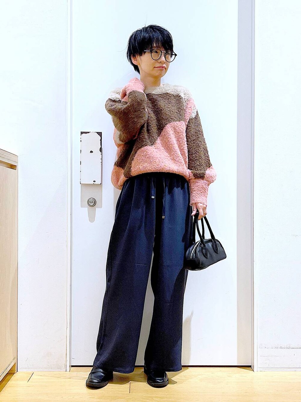 ブラック系のローファー、ピンク系のニット/セーター、ブラック系のボストンバッグを着用したレディースの冬コーディネートの2枚目の写真