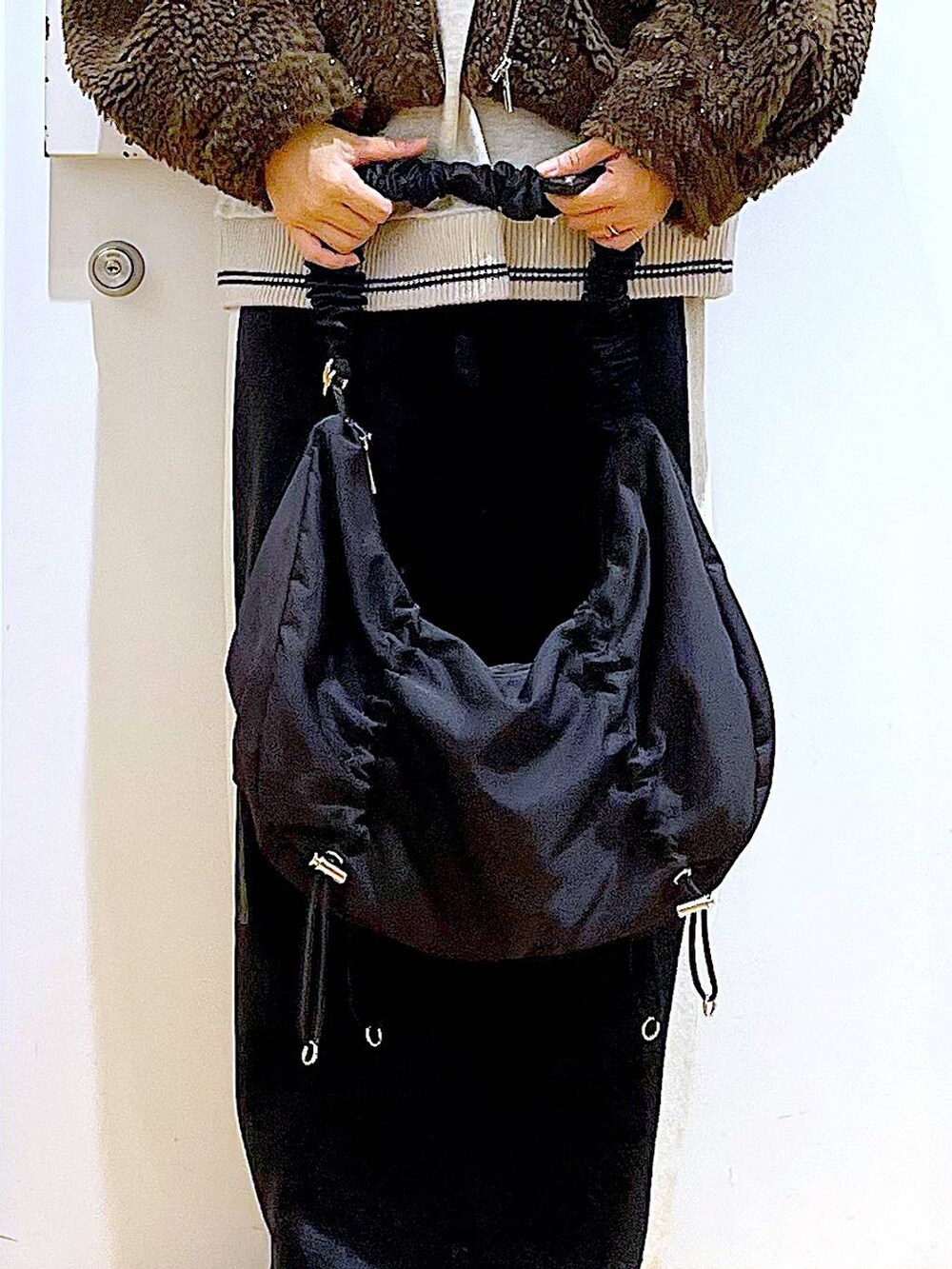 ブラック系のスカート、ブラック系のショルダーバッグ、ブラック系のブーツを着用したレディースの冬コーディネートの9枚目の写真